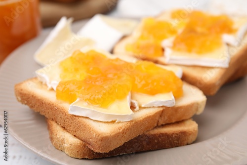 Tasty sandwiches with brie cheese and apricot jam on plate, closeup