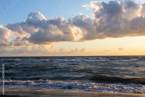 Beautiful sunset over the sea. Waves  clouds and black sand