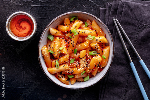 Tteokbokki or topokki, Korean street food, spicy rice cakes, overhead flat lay shot with chopsticks and a drink photo