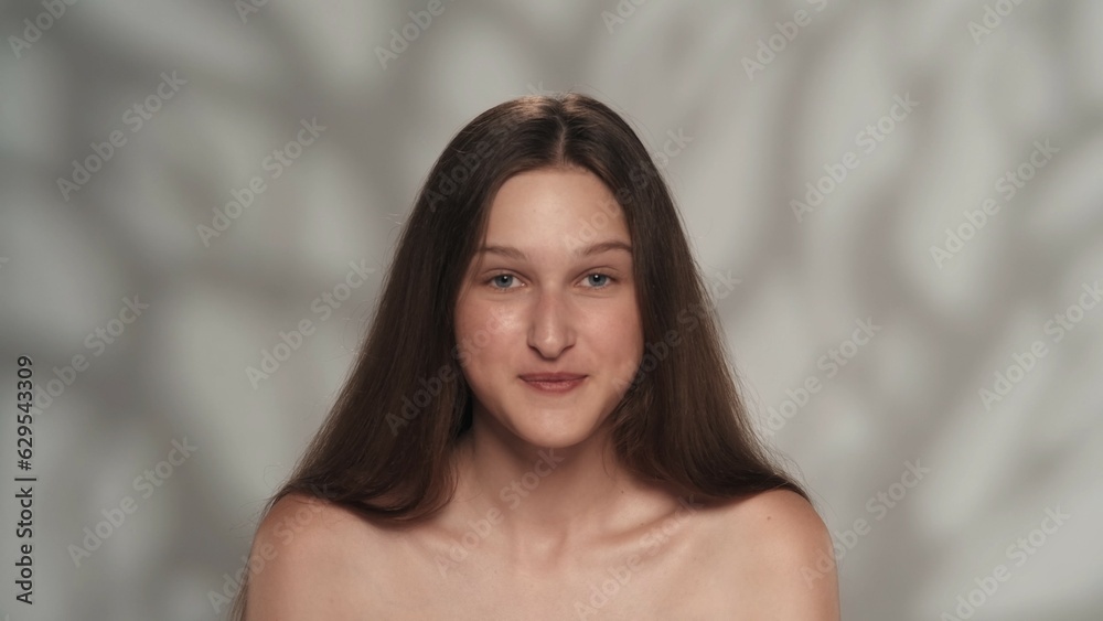 Appealing female model with long shiny hair and natural makeup looking at the camera Appealing female model with long shiny hair and natural makeup looking at the camera