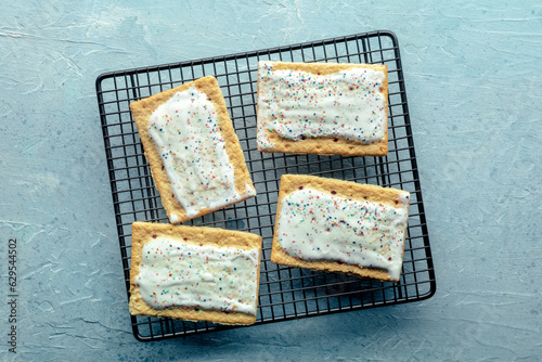 Pop tarts on a baking rack. Poptart toaster pastry with icing on a blue slate background, overhead flat lay shot