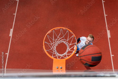 Close-up of a basketball ring into which a tall guy basketball player throws the ball from below the concept of admiring the game of basketball