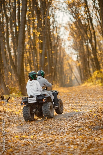 Man and woman driving quad bike in autumn forest