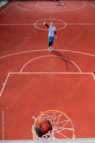Close-up of a basketball ring into which a tall guy basketball player throws the ball The concept of admiring the game of basketball