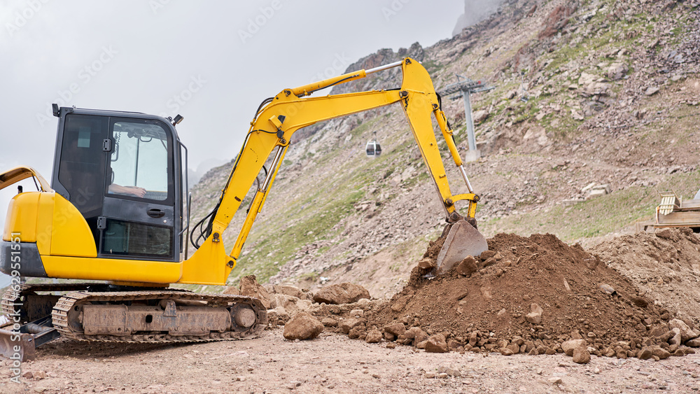 Excavator works in the highlands. Makes a trench for communications. water and electricity. in the gorge of the mountains. repair and expansion of a road