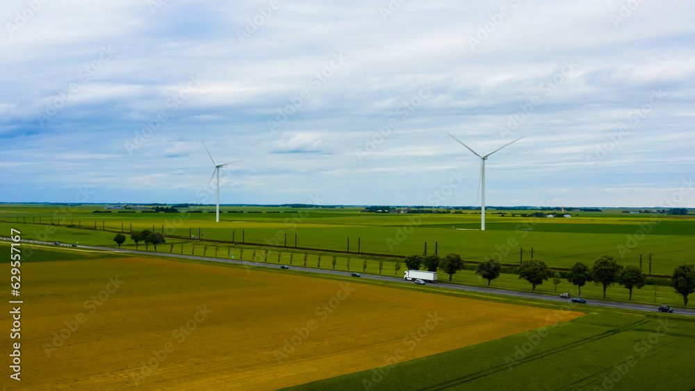 Wind turbines stand tall against the backdrop of farmland under cloudy skies Wind turbines stand tall against the backdrop of farmland under cloudy skies