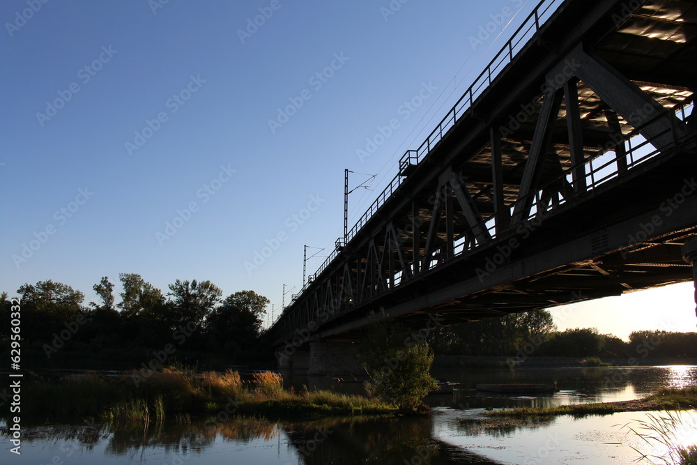 A bridge over water with trees and blue sky