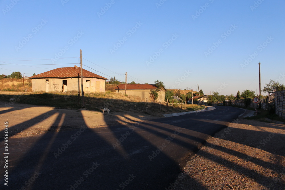 A road with a building and shadows on the ground