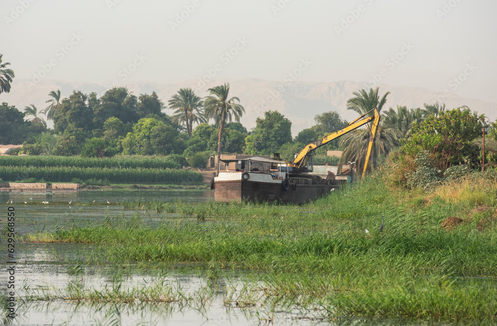Fototapeta premium Landscape view across african river with dredging barge
