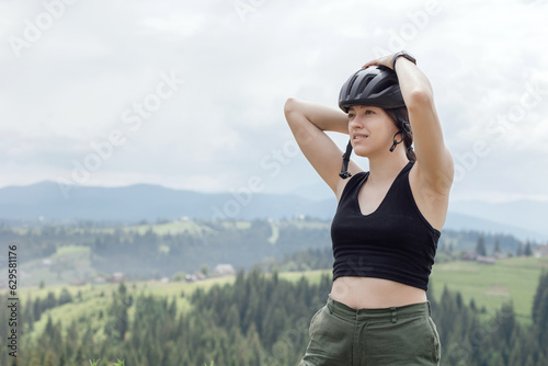 Woman cyclist fix bicycle helmet to ride a bicycle in mountains