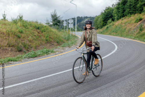 Fototapeta Naklejka Na Ścianę i Meble -  Young woman cyclist enjoy the beautiful view on green mountains trail