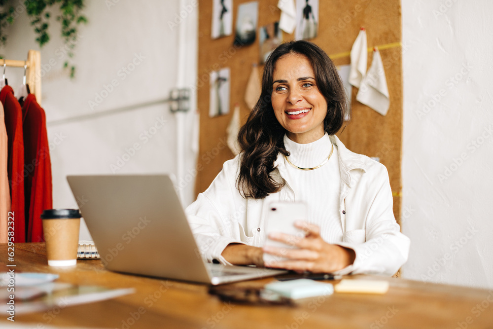 Creative business woman working with mobile technology to market her fashion design startup online Creative business woman working with mobile technology to market her fashion design startup online
