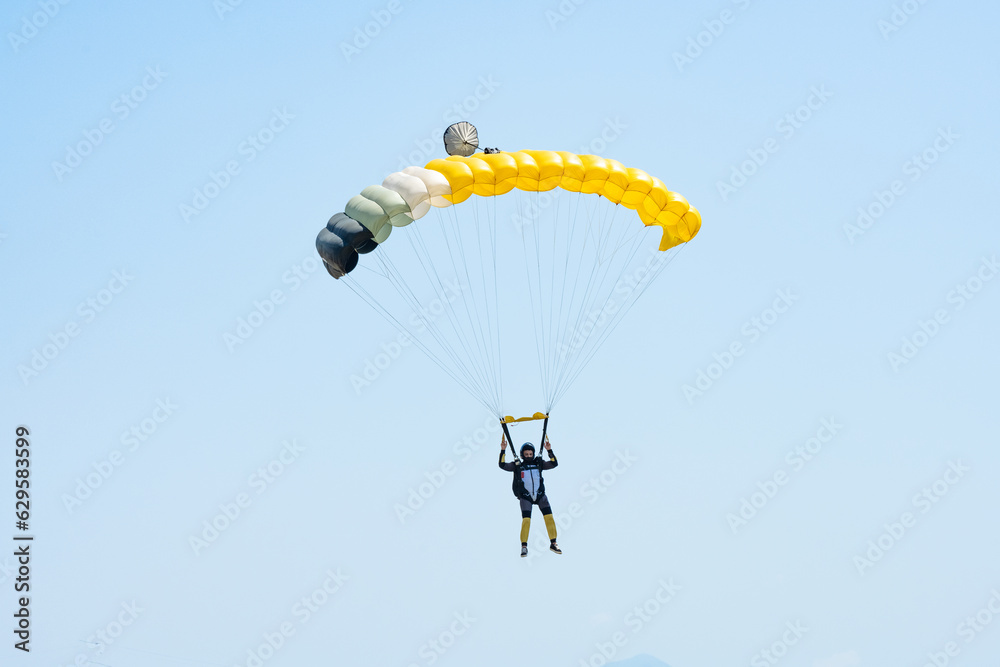 Stunning view of of a skydiver with a yellow parachute and a blue sky in the background.