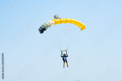 Stunning view of of a skydiver with a yellow parachute and a blue sky in the background.