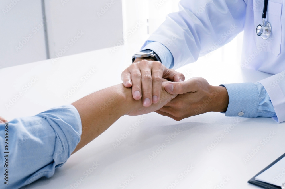 Doctor holding patient's hand, and reassuring his male patient helping hand conceptใ