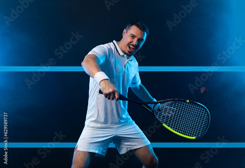 Squash player on a squash court with racket. Man athlete with racket on court with neon colors. Sport concept. Download a high quality photo for the design of a sports app or betting site. © Mike Orlov