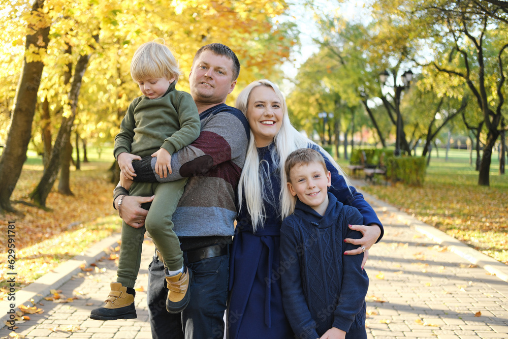 Family of four posing in autumn park, looking at camera and smiling Family of four posing in autumn park, looking at camera and smiling
