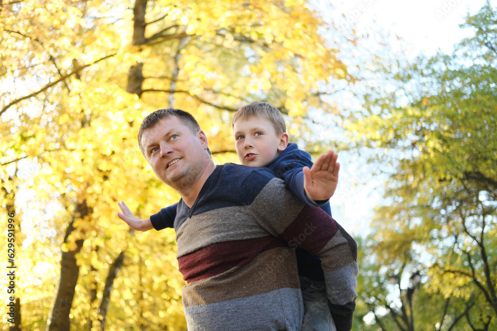 Son and father have fun playing airplanes outdoors on a sunny autumn day. Son and father have fun playing airplanes outdoors on a sunny autumn day.