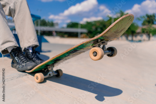 Close-up of a skateboard being held by the foot of a young skateboarder in a city skatepark 