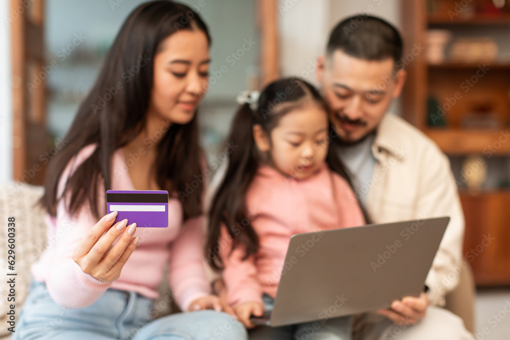 Asian family with laptop and card browsing internet stores indoor Asian family with laptop and card browsing internet stores indoor