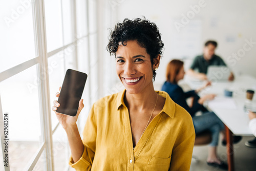 Business woman holding up a mobile phone in an office