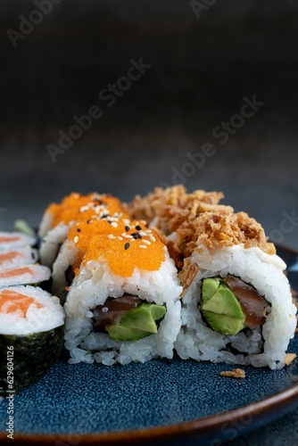 Vertical closeup shot of assorted sushi rolls on a blue plafe