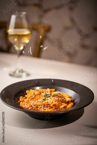 Bowl of delicious penne pasta with cheese and sauce on the table