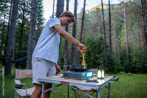 A boy cooking in the forest.