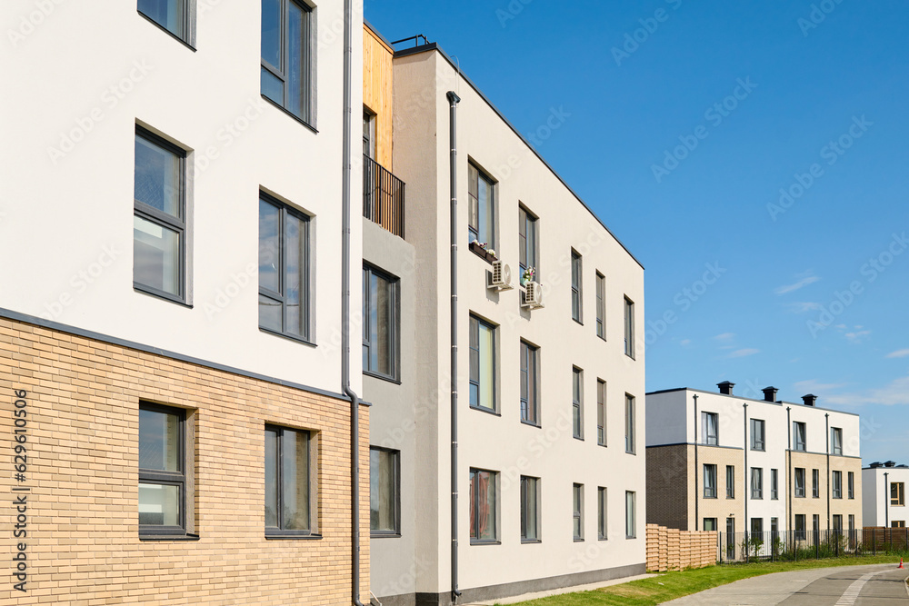 Perspective of long white three storey block of flats with windows standing along road in central street of non-urban area Perspective of long white three storey block of flats with windows standing along road in central street of non-urban area