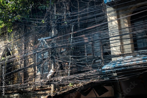 photograph of an electric pole with lots of cables on it on the street of Bangkok.