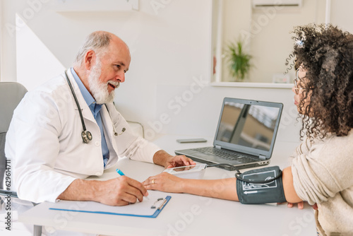 a senior doctor measuring a female patient s blood pressure in his office