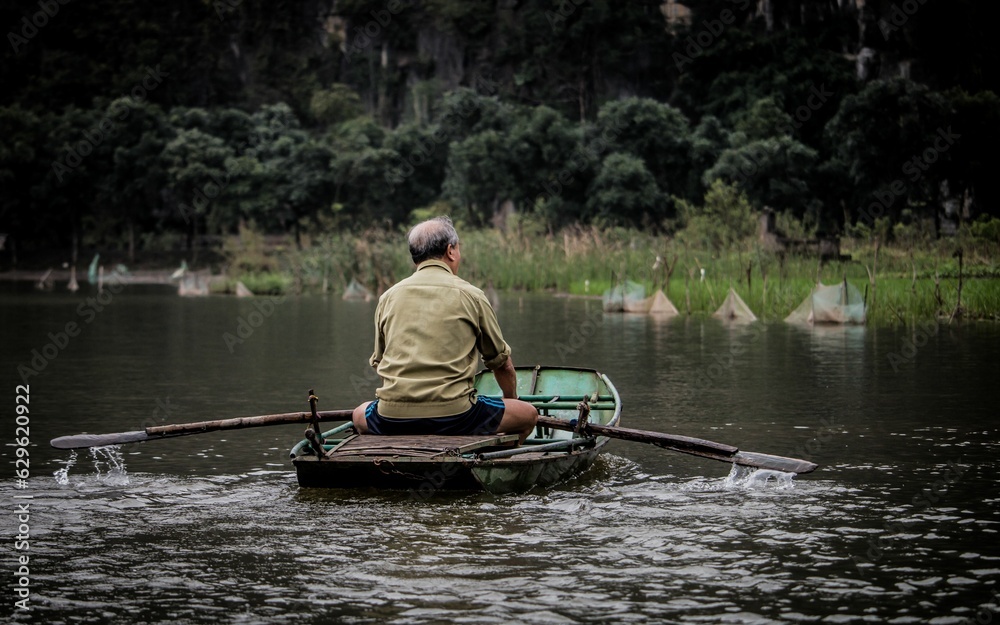 Man in a canoe is savoring the serene beauty of a tranquil lake on a sunny day in Vietnam Man in a canoe is savoring the serene beauty of a tranquil lake on a sunny day in Vietnam