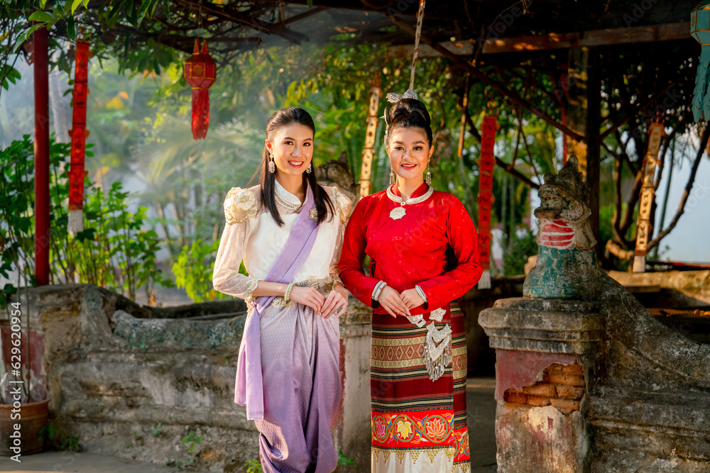 Obraz premium Close up portrait of two beautiful Asian woman stand in front of old or ancient architecture or building look like temple of northern Thailand.