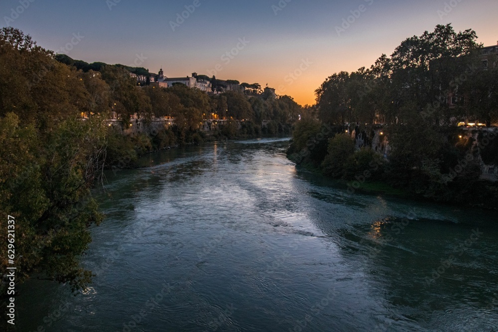 Tiber River in Rome at sunset, illuminated by the golden rays of the setting sun