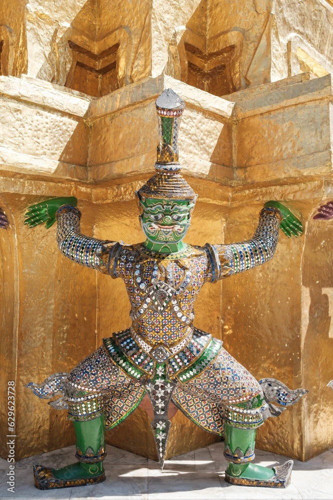 a statue in an elaborate suit standing against a gold wall