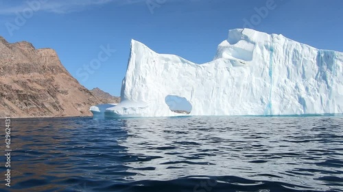 Giant iceberg with hole, barren mountains, summer in the Arctic, Tasilaq, Denmark, Greenland, North America photo