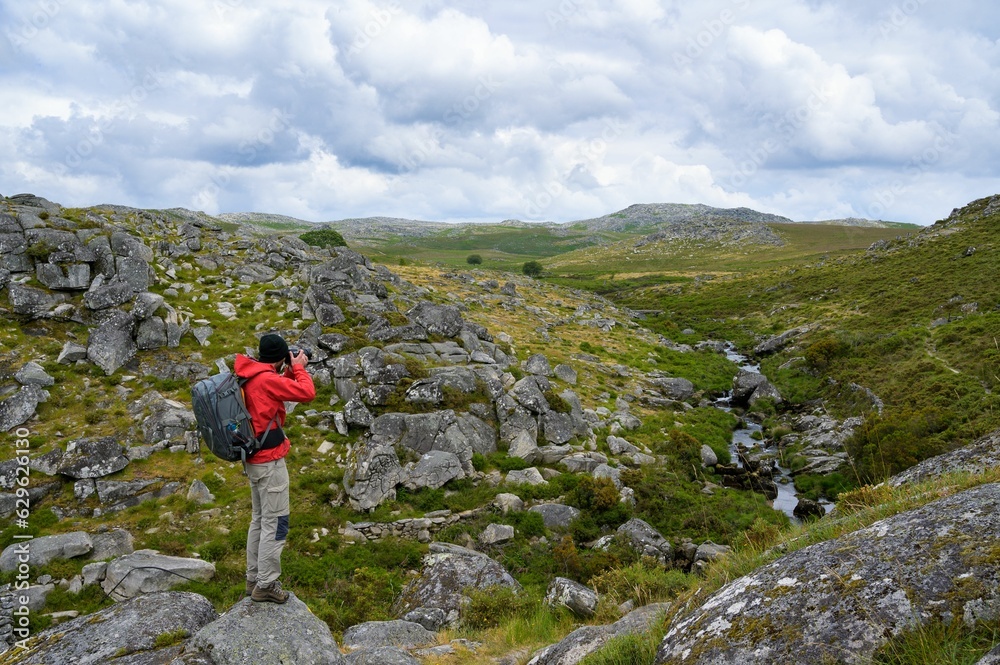 Hiker taking pictures of the scenic rocky highland. Serra da Freita, Portugal.