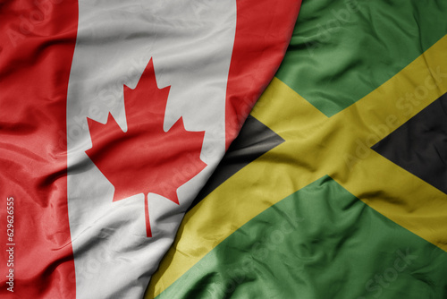 big waving realistic national colorful flag of canada and national flag of jamaica .
