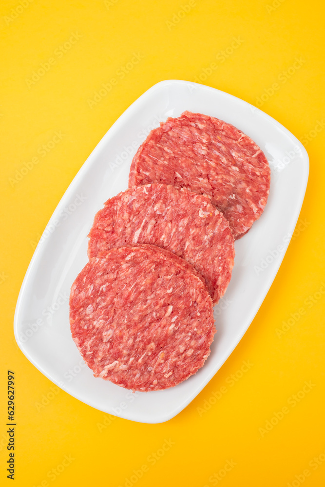 Three raw red meat burgers for hamburgers of minced ground beef on dish Three raw red meat burgers for hamburgers of minced ground beef on dish
