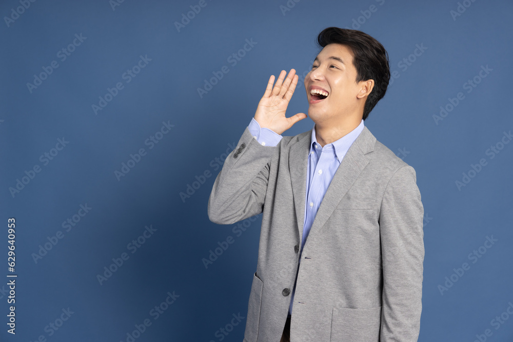 Young Asian business man shout loudly isolated on blue background, Speaker and announce concept Young Asian business man shout loudly isolated on blue background, Speaker and announce concept
