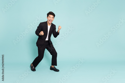 Young Asian business man shout loudly and be very happy isolated on green background