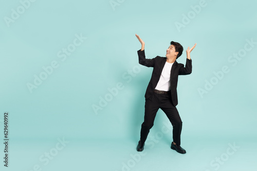 Shocked Asian businessman and looking up on top isolated on green background photo