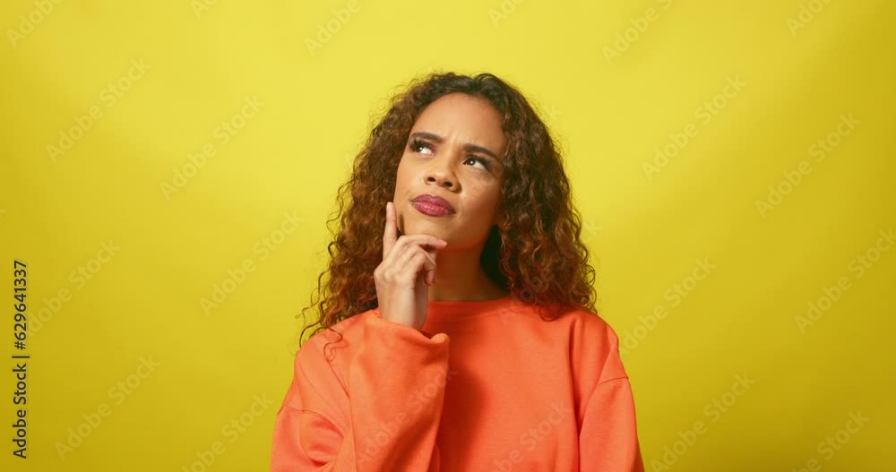 Serious young woman thinking and contemplating, yellow studio background Serious young woman thinking and contemplating, yellow studio background