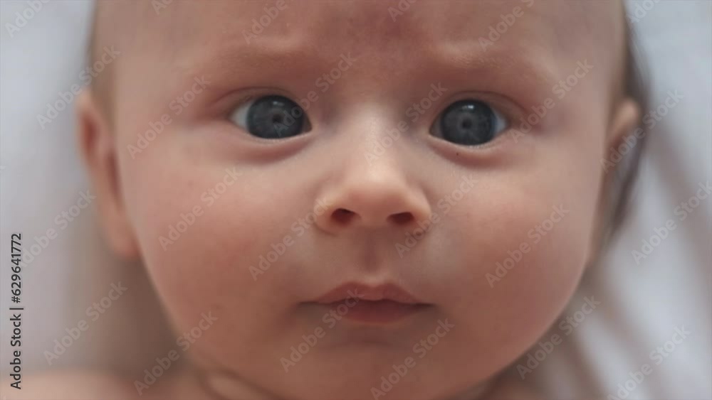Close-up top view portrait of peaceful cute Caucasian newborn infant boy. Curious smart adorable kid toddler lying on comfortable white bed at home. Childcare, bedtime, daily routine concept Close-up top view portrait of peaceful cute Caucasian newborn infant boy. Curious smart adorable kid toddler lying on comfortable white bed at home. Childcare, bedtime, daily routine concept