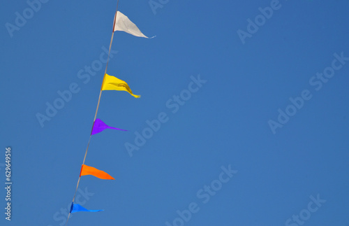 Multicolored triangular small flags to celebration party against blue sky.Street holiday concept for design.Selective focus. 