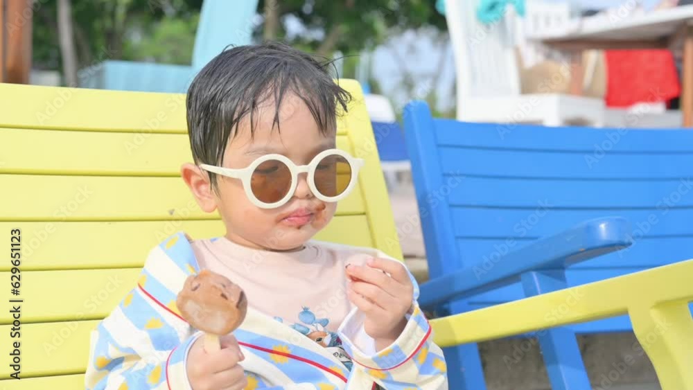 Asian boy sitting on a beach chair eating ice cream. Asian boy sitting on a beach chair eating ice cream.