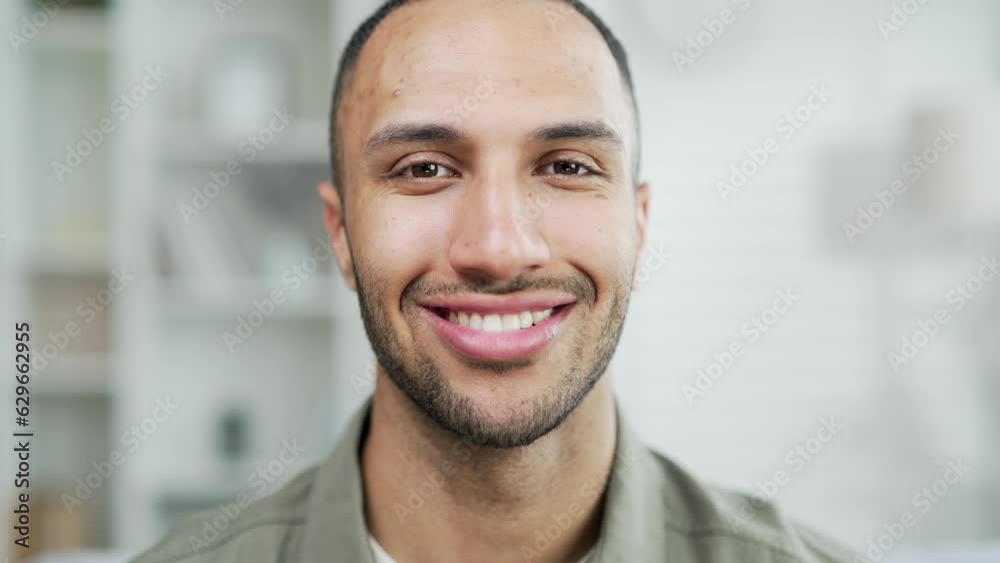 Portrait happy smiling handsome man looking at camera in the living room at home. Young adult mixed race male joyful positive in casual shirt indoors satisfied contented face expression indoor closeup