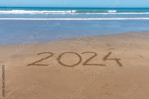 2024 written in the sand on the seashore with the arrival of the wave.