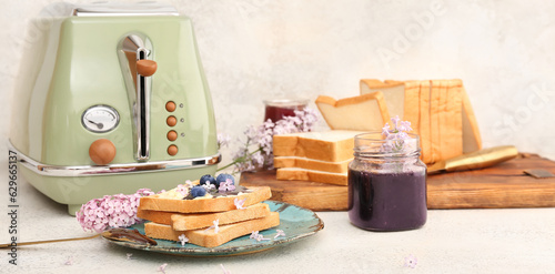 Plate with sweet blueberry jam toasts and toaster on grunge background