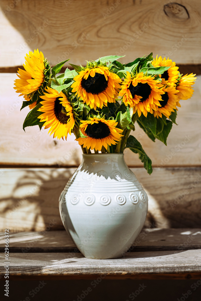 Bouquet of sunflowers in a ceramic white vase on a wooden background
Bouquet of sunflowers in a ceramic white vase on a wooden background
